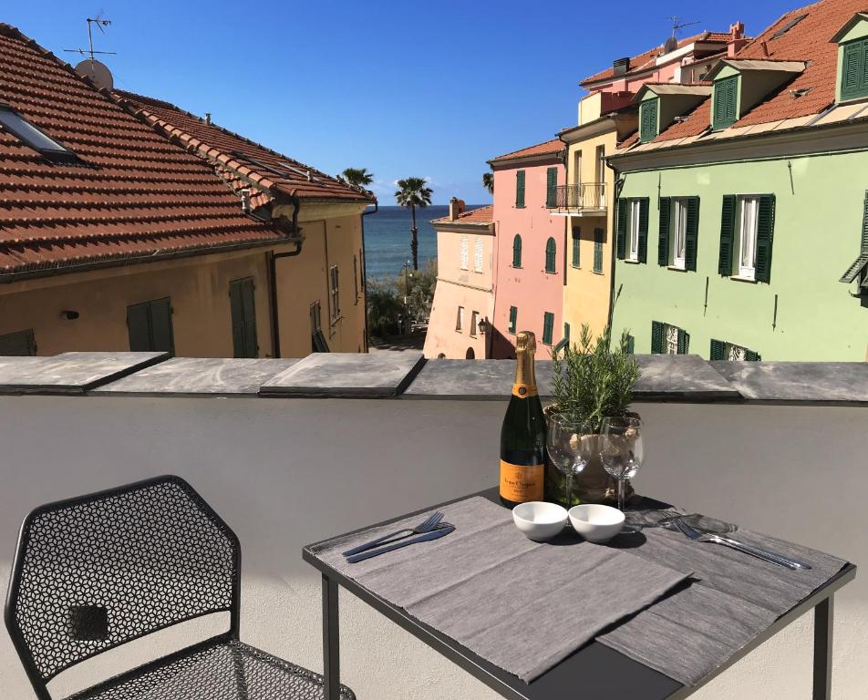 a table and a bottle of wine on a balcony at Case Antico Comune in San Lorenzo al Mare