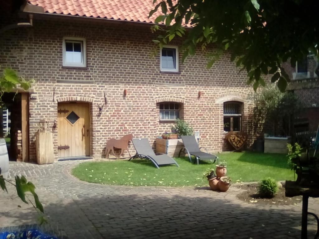 una casa de ladrillo con dos sillas en el patio en Ferienwohnung Hoffmann en Gangelt