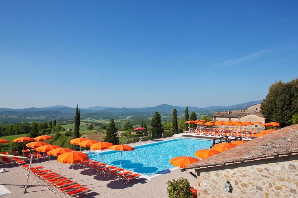 ein Resort mit einem Pool mit orangefarbenen Sonnenschirmen in der Unterkunft Hapimag Resort Pentolina in Chiusdino