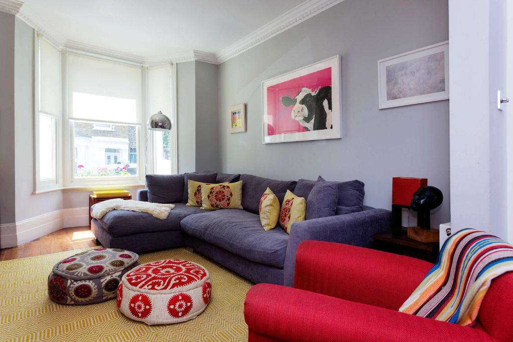 a living room with a blue couch and red chairs at Veeve - Heaven in Highgate in London