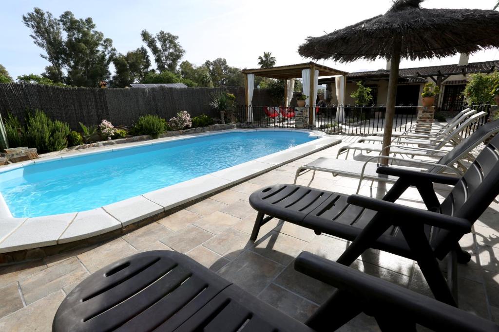 a swimming pool with chairs and an umbrella at Llano San Ignacio in El Bosque