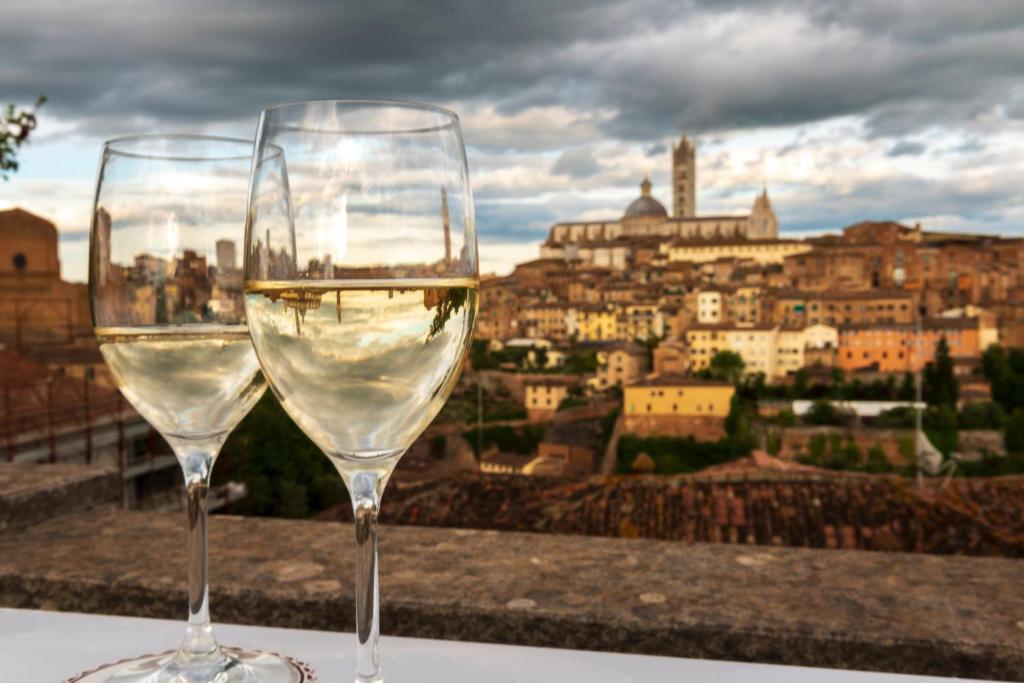 two wine glasses sitting on a ledge with a view of a city at Villa Elda Boutique Hotel in Siena