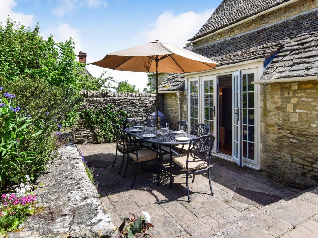 a table and chairs with an umbrella on a patio at Cotswold Cottage in Cirencester