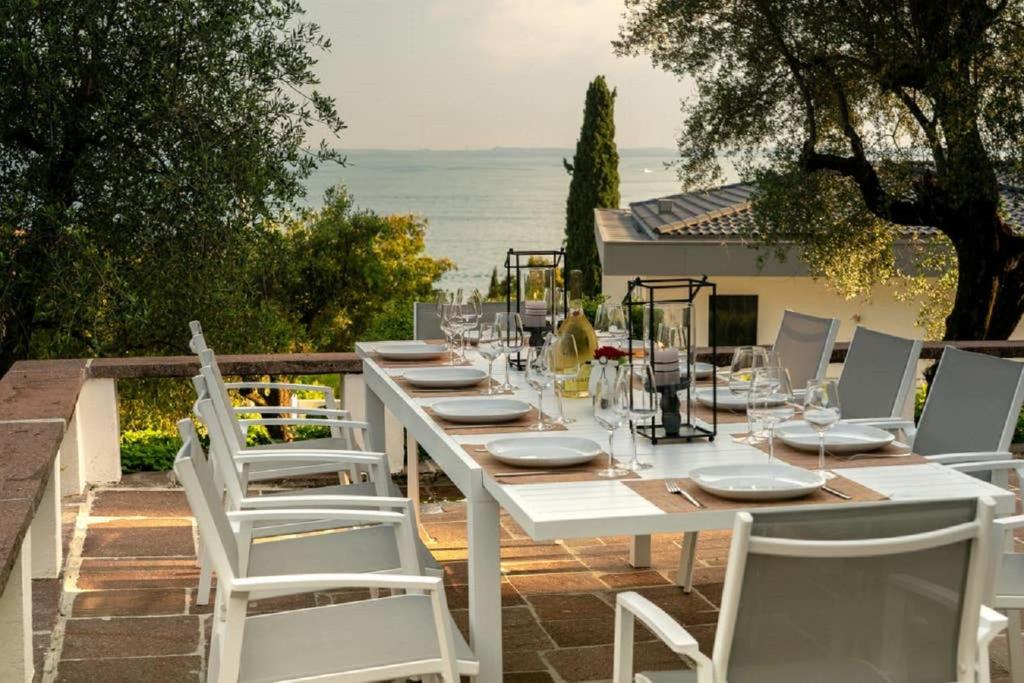 a long white table with white chairs and the ocean at Gardavilla Limoni am See in Garda