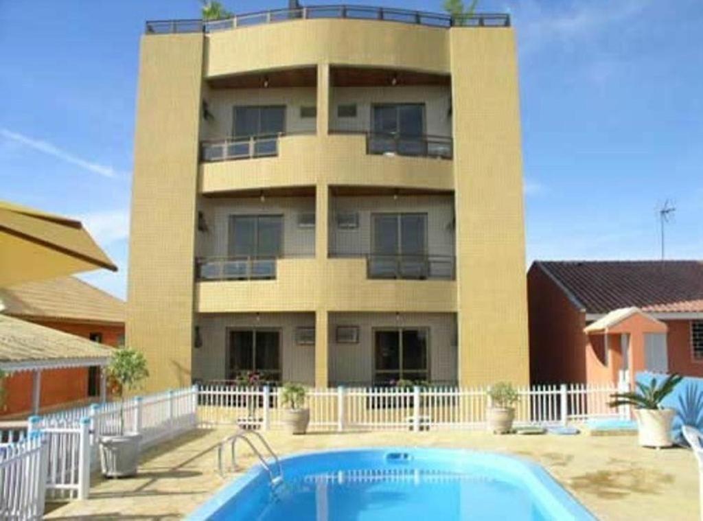 a building with a swimming pool in front of a building at Hotel Pousada Mineirinho in Balneário Praia do Leste