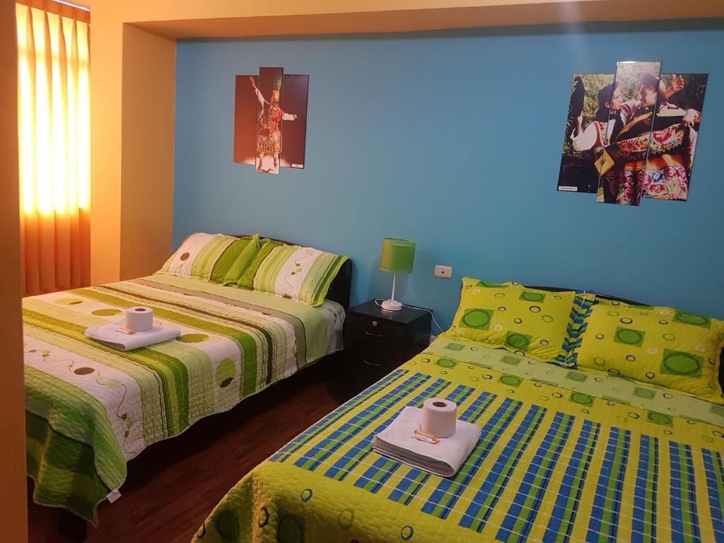 Hostal Los Pinos في وانكايو: غرفة نوم بسريرين وجدار ازرق