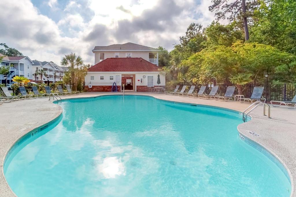 a large swimming pool with chairs and a house at Green Arbor in North Myrtle Beach