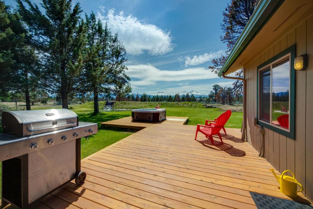 a wooden deck with a grill and a red chair on it at Apache Greens in Sisters