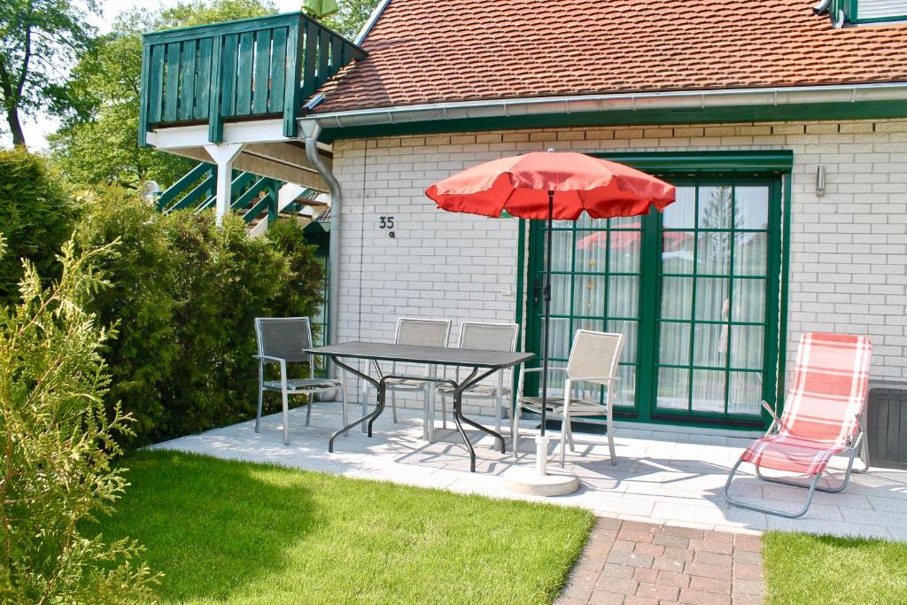 a table and chairs with a red umbrella on a patio at Ostseehaus Prerow in Prerow