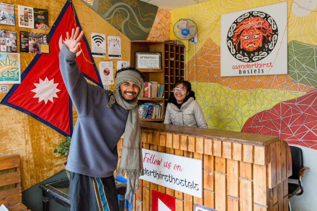 a man standing in front of a counter with his hand in the air at Wander Thirst in Kathmandu