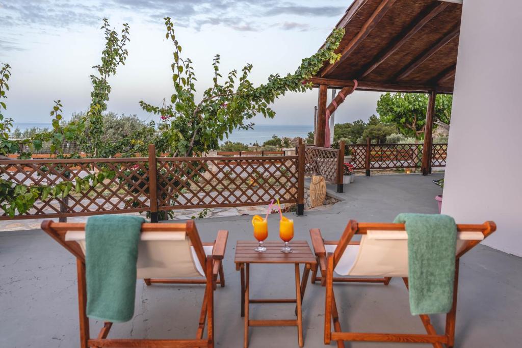 un patio con 2 sillas y una mesa con bebidas. en Ktima Argyrou Stegna, en Archangelos