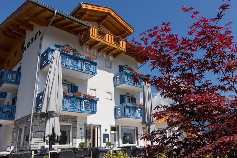 a white building with blue balconies and an umbrella at Hotel Milano in Tione di Trento