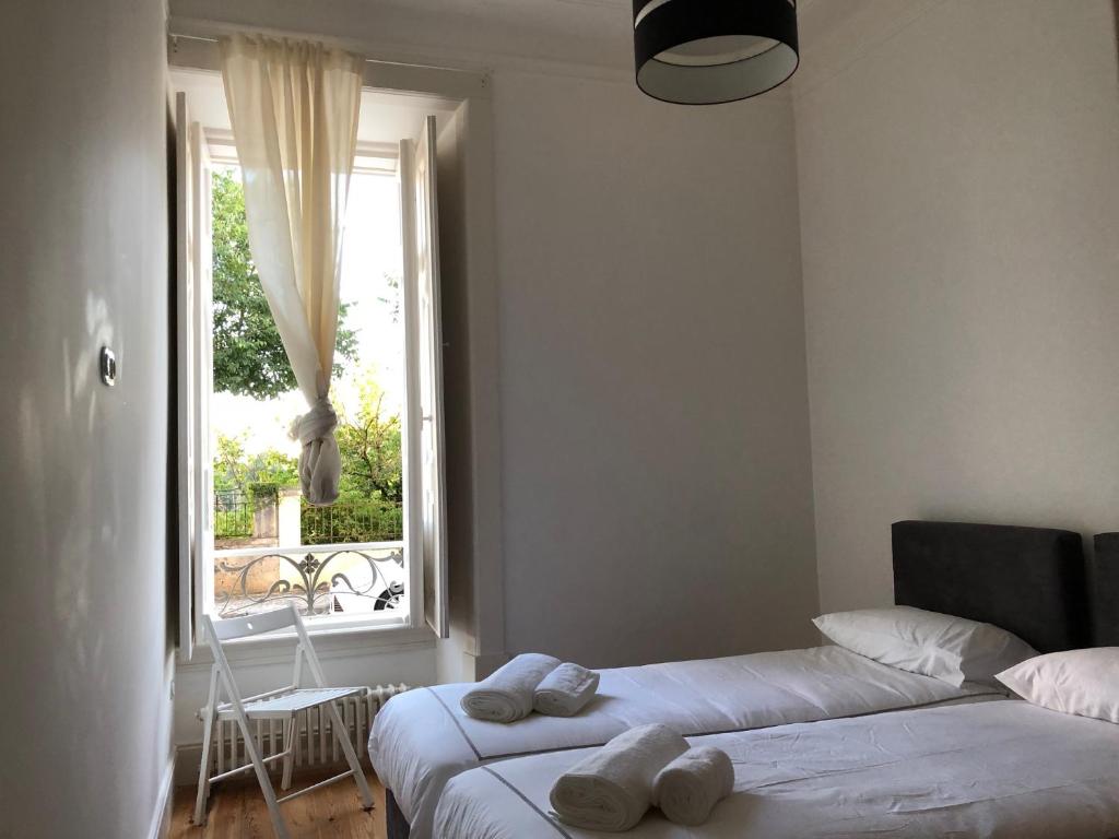 een slaapkamer met 2 bedden en een raam met een stoel bij Rua Tenente Campos Rego, Ground Floor in Coimbra