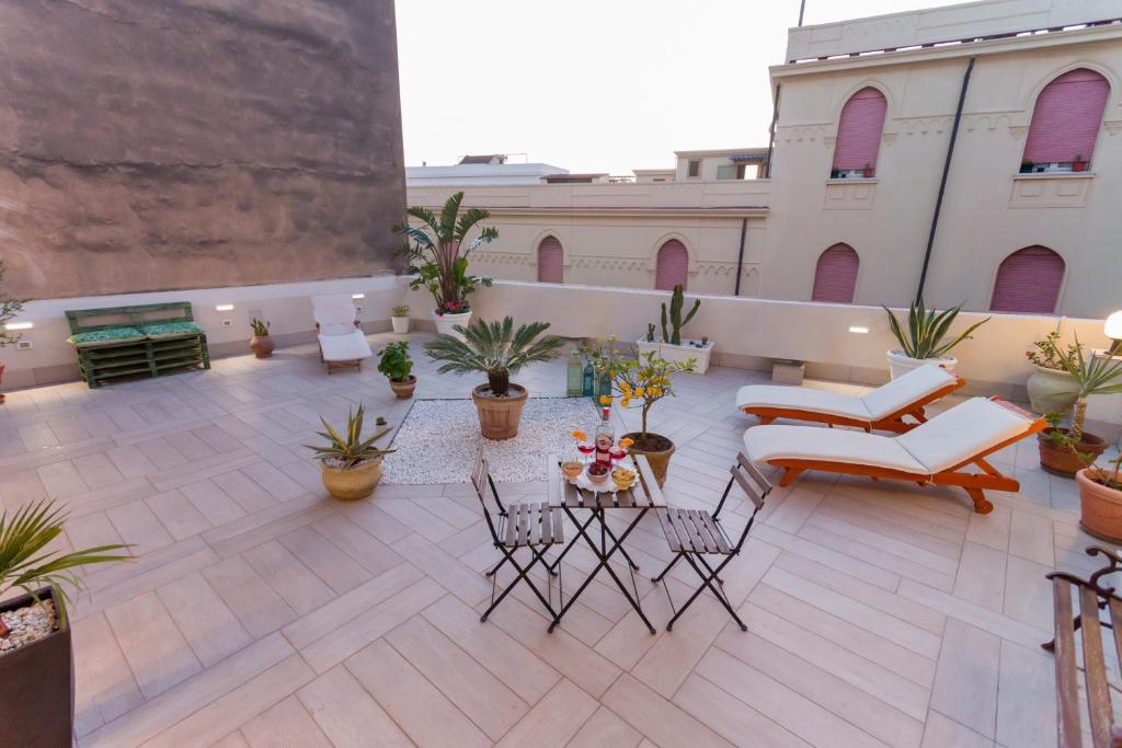 Un patio en la azotea con sillas, mesas y plantas en macetas. en B&B Kalavrìa, en Reggio Calabria