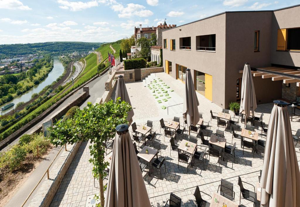 einen Balkon mit Sonnenschirmen und Tischen sowie ein Gebäude in der Unterkunft Schlosshotel Steinburg in Würzburg