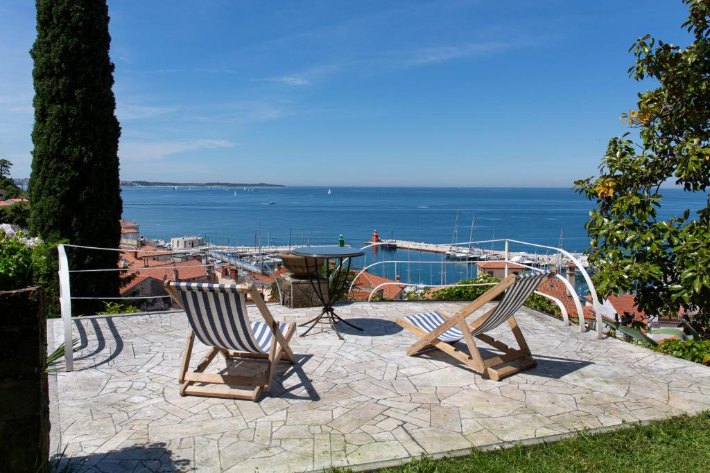 2 Stühle und ein Tisch auf einer Terrasse mit Meerblick in der Unterkunft Mediterranean Villa with an Amazing View and a Pool by Loft in Piran