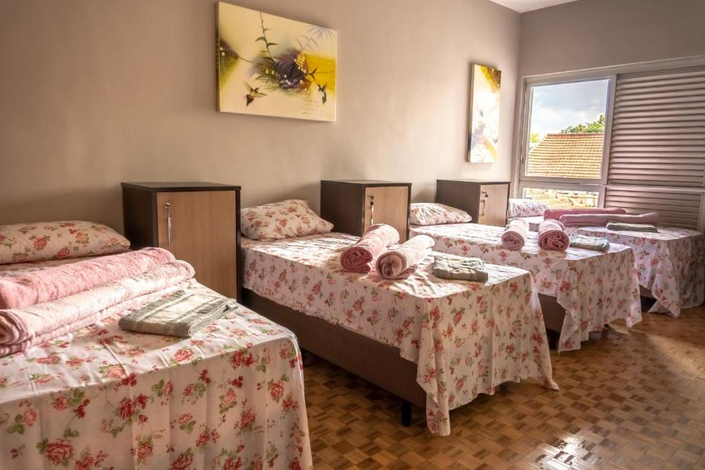 a group of four beds in a room with tables at Hostel Senhor do Café in Botucatu