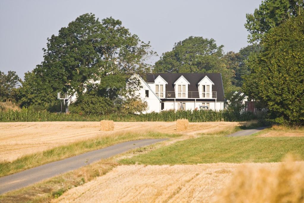 a white house with a black roof and a road at Quistgaarden Bed & Breakfast in Spjellerup