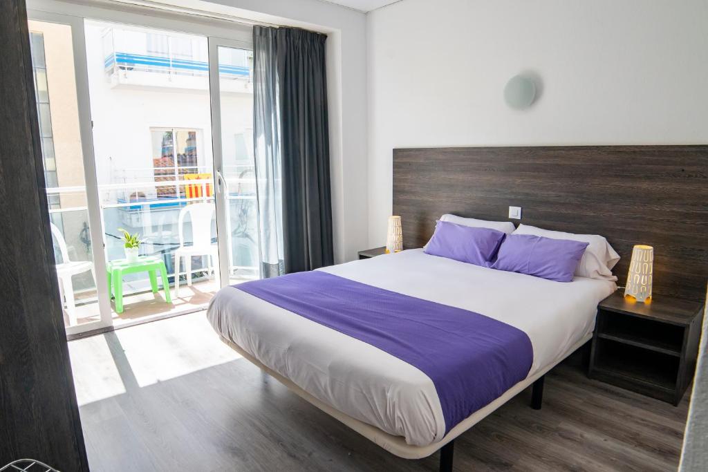 - une chambre avec un grand lit et des oreillers violets dans l'établissement Apartaments Atzavara, à Calella