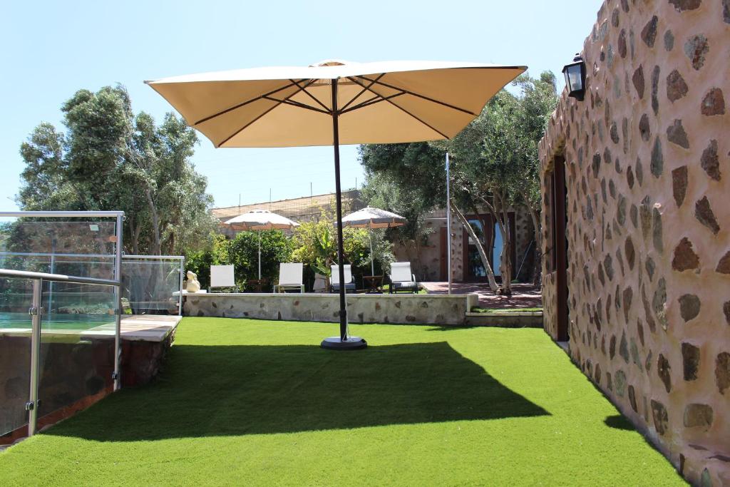 a patio with an umbrella and green grass at Villa Cantos Colorados in Ingenio