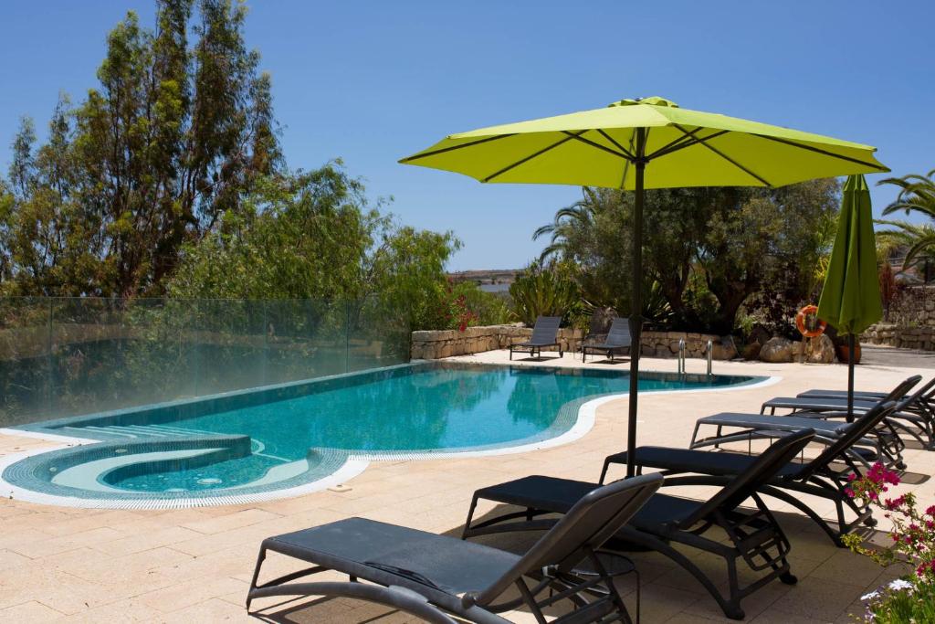 einen Pool mit Stühlen und einem Sonnenschirm in der Unterkunft La Malvasía in Arico Viejo