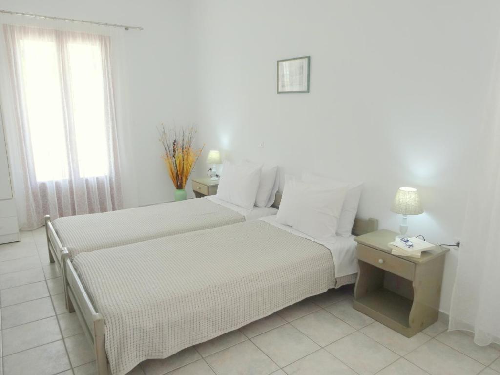 two beds in a room with white walls and windows at Kamakaris Rooms in Adamantas