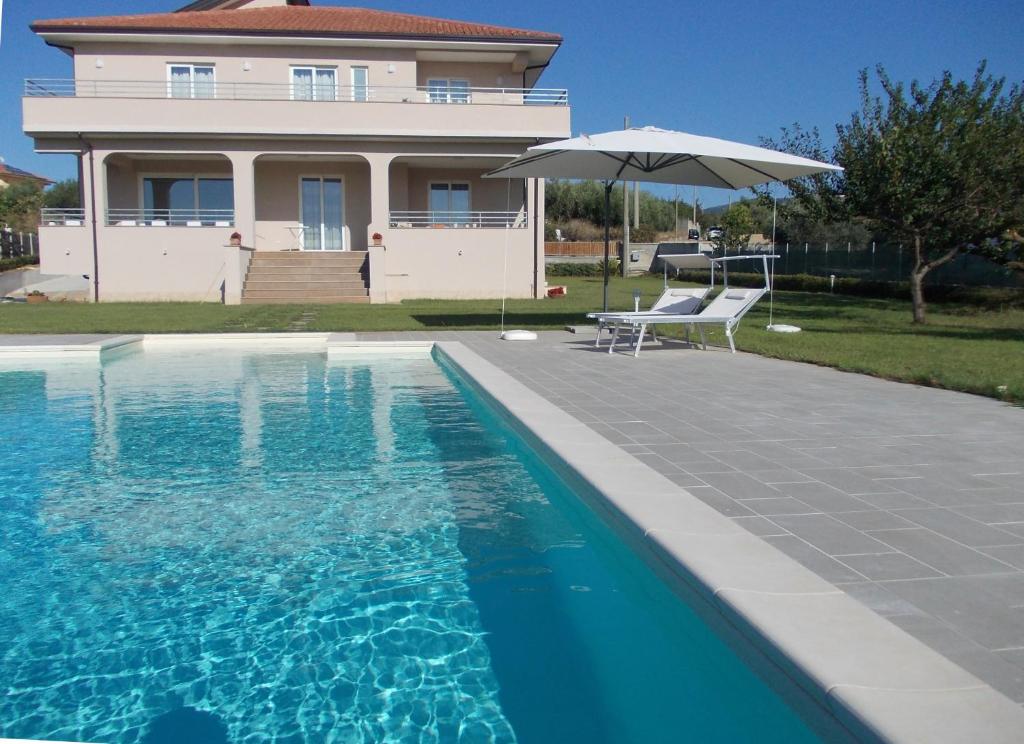 uma casa com piscina e guarda-sol em VILLA LAURO LUXURY B&B em Castellabate