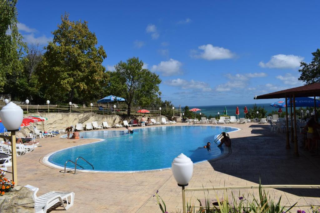 uma grande piscina com pessoas sentadas à sua volta em Ahilea Hotel - Free Pool Access em Balchik