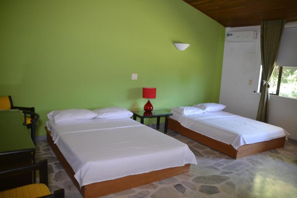 two beds in a room with green walls at Hotel Albatros in El Espinal