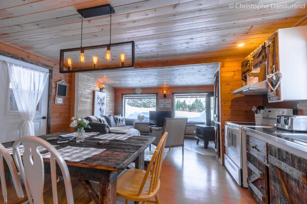 uma cozinha e sala de jantar com uma mesa numa pequena casa em Chalet Le Pti Loup - Les Chalets Spa Canada em La Malbaie