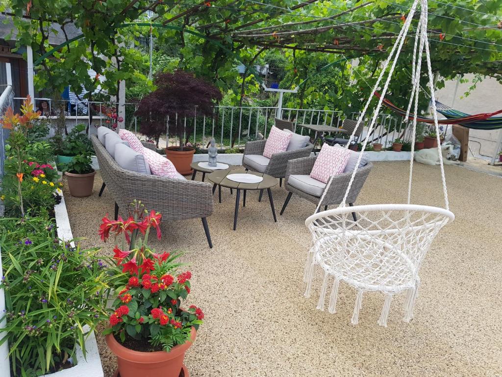 un patio con varias sillas, mesas y flores en Ilir Guest House 1, en Përmet