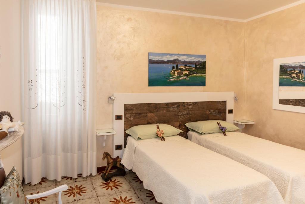 sypialnia z 2 łóżkami i oknem w obiekcie Casa Vacanze Agnese w mieście San Felice del Benaco