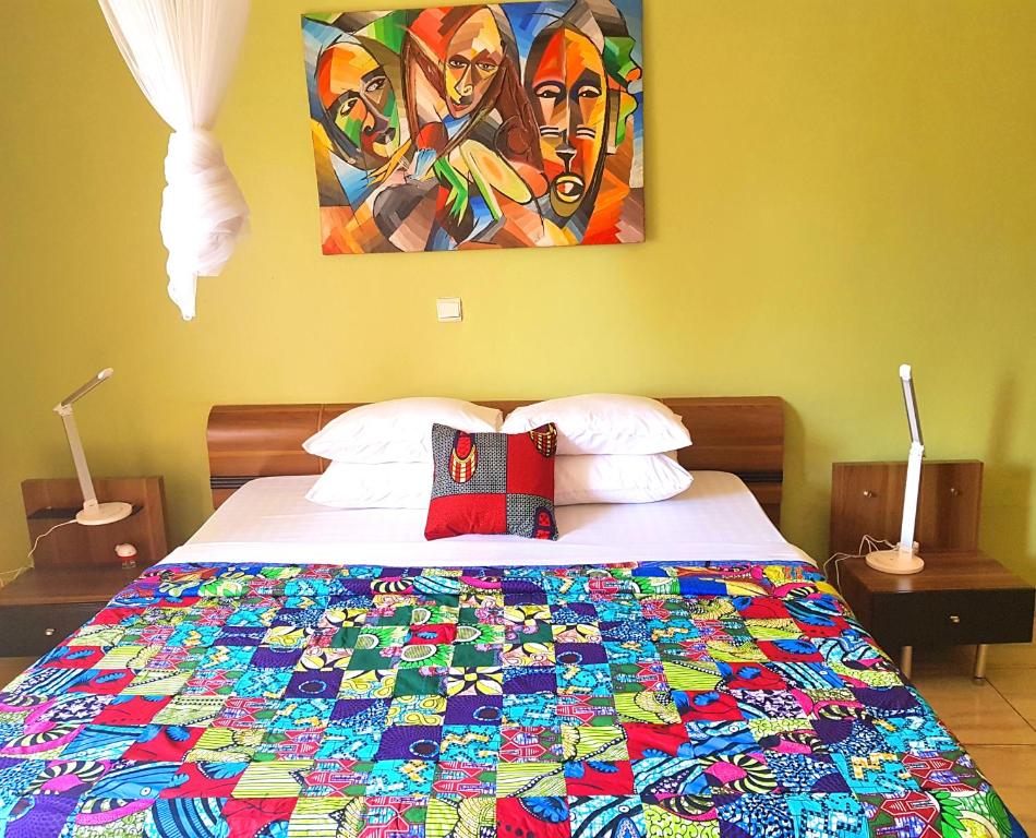 a bedroom with a bed with a colorful quilt on it at Yambi Guesthouse in Kigali