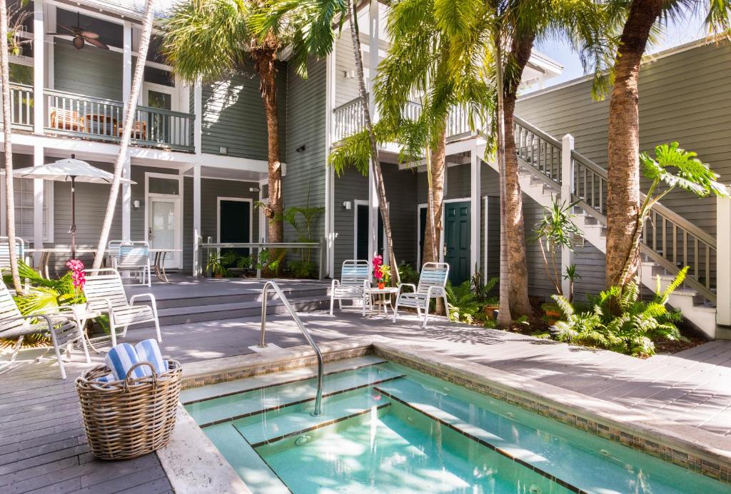 a swimming pool in front of a house with palm trees at The Cabana Inn Key West - Adult Exclusive in Key West