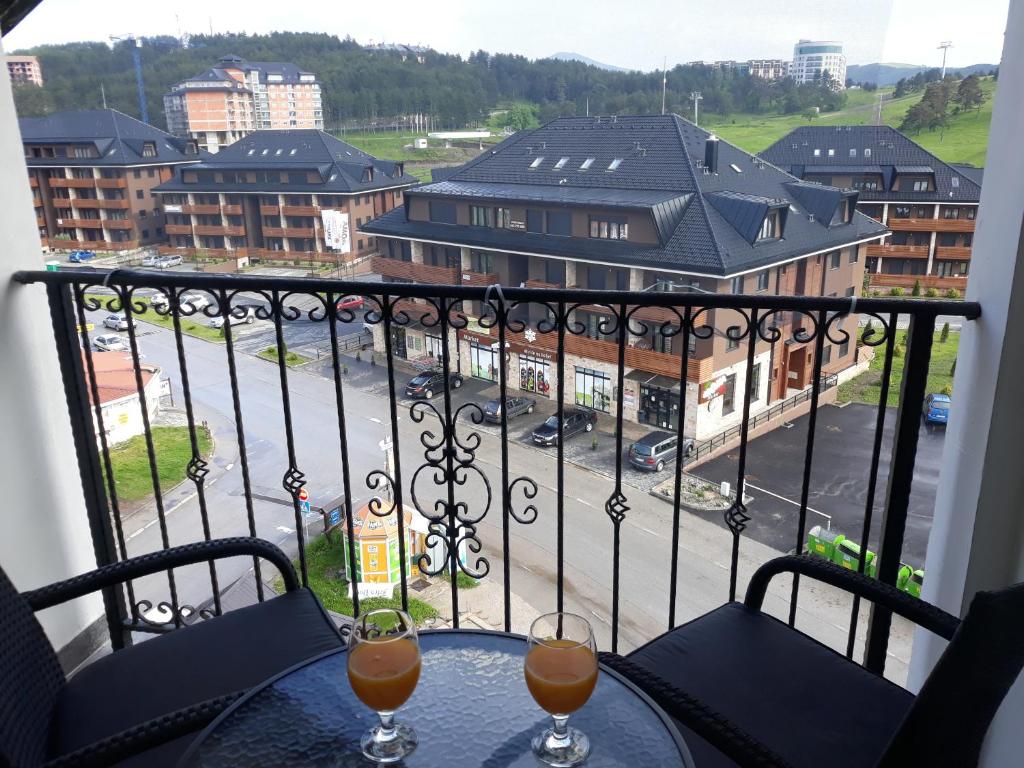 a table with two glasses of wine on a balcony at Pejzaž Zlatibora, primamo vaucere! in Zlatibor