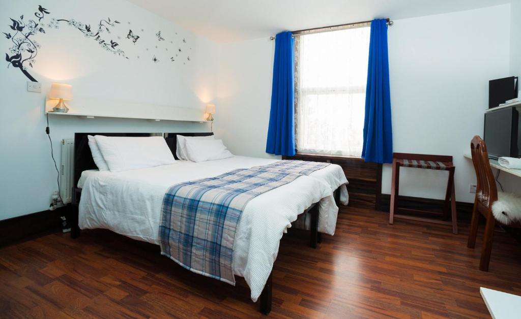a bedroom with a bed and a window with blue curtains at Breeze Guest House in Bootle