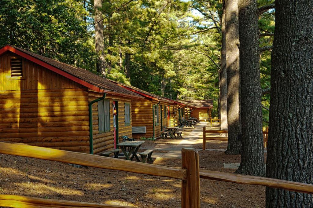 a log cabin with a fence in front of it at Log Cabins at Meadowbrook Resort in Wisconsin Dells