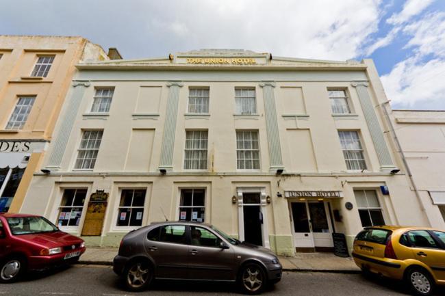 a building with two cars parked in front of it at Union Hotel in Penzance