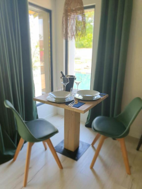 a wooden table with two green chairs and a table with plates at Les Granges de Jules in Lafitte-Vigordanne