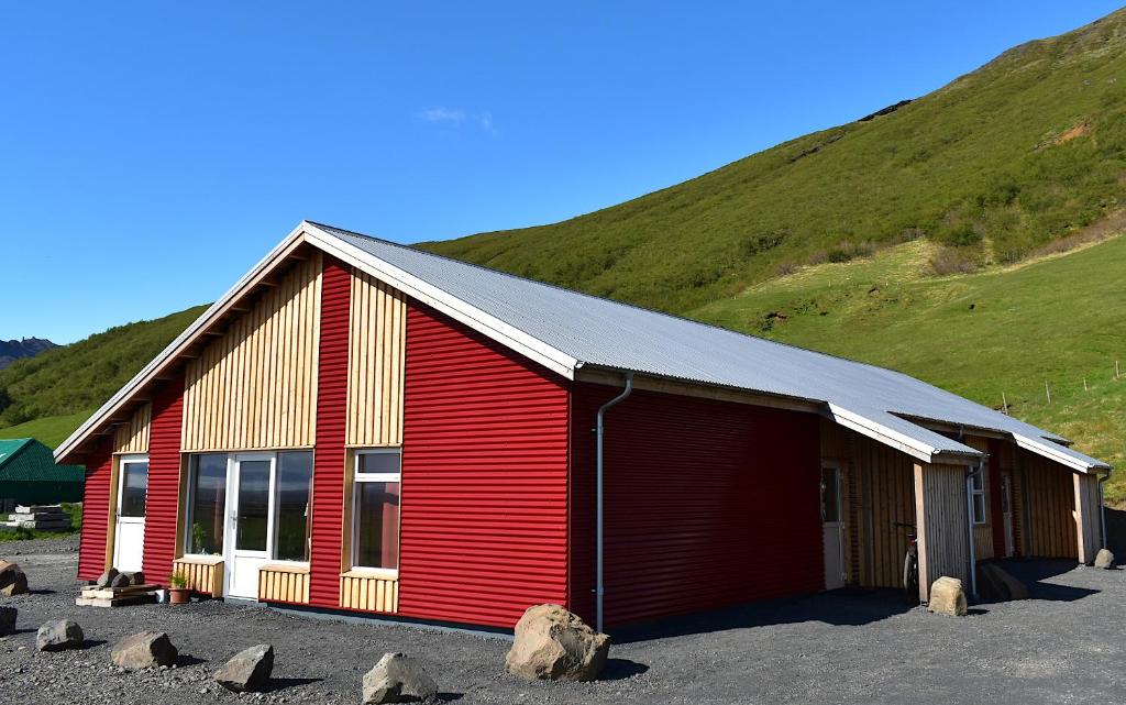 ein rotes Gebäude mit einem Hügel im Hintergrund in der Unterkunft The Potato Storage in Svínafell