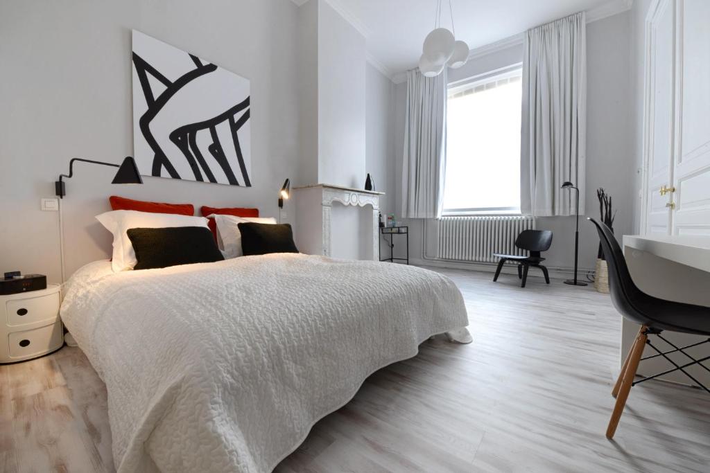 a white bedroom with a large bed and a desk at B&B Villa Chantecler in Bruges