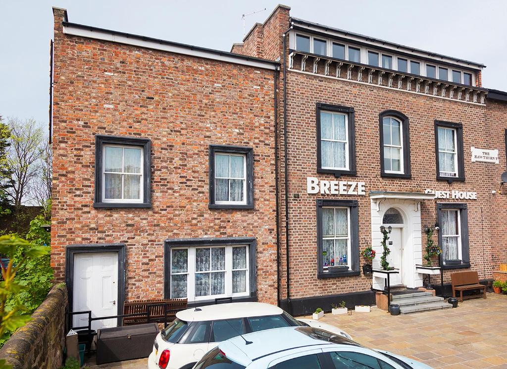 a brick building with a car parked in front of it at Breeze Guest House in Bootle