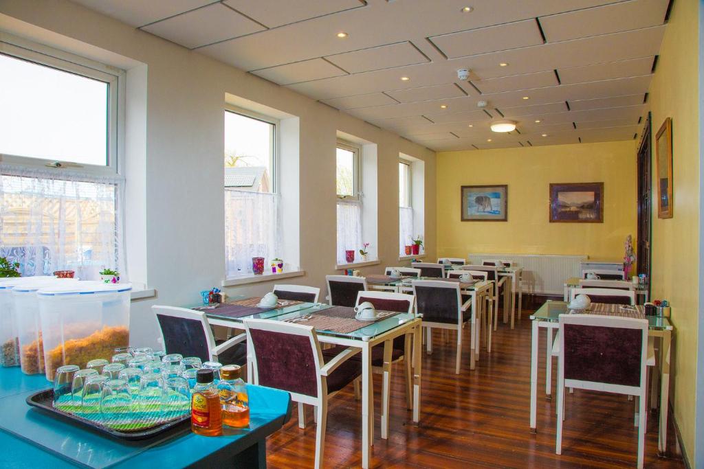 a dining room with tables and chairs and windows at Breeze Guest House in Bootle
