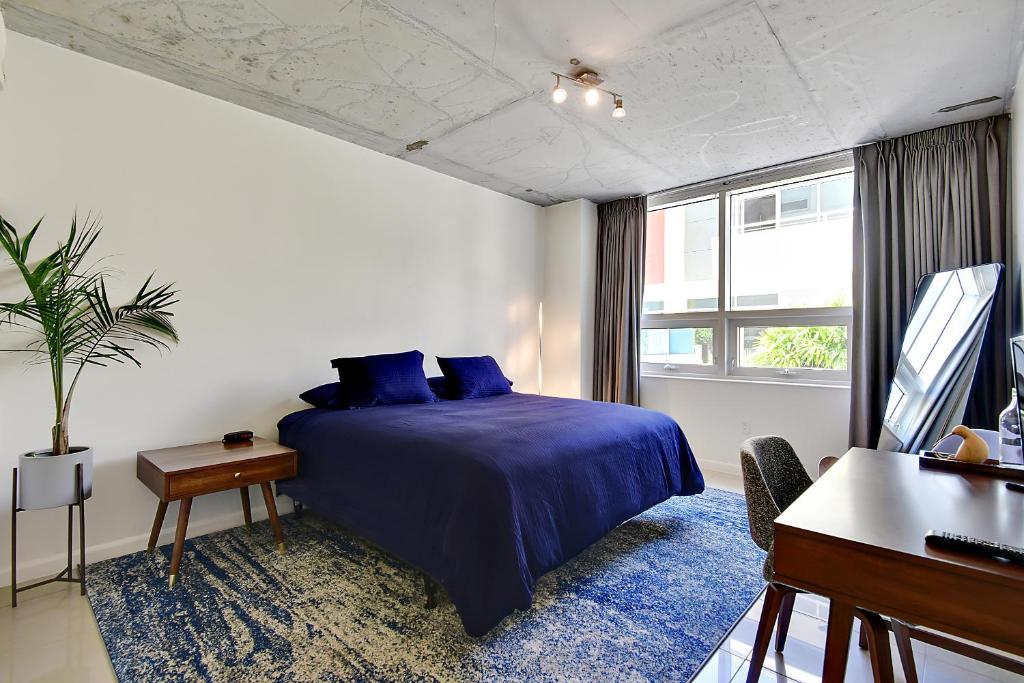Un dormitorio con una cama azul y un piano en Miami Midtown Luxury Apartment, en Miami