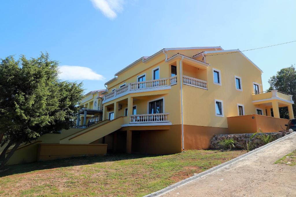 a yellow building with a balcony on the side of it at Apartments Galboka in Nerezine