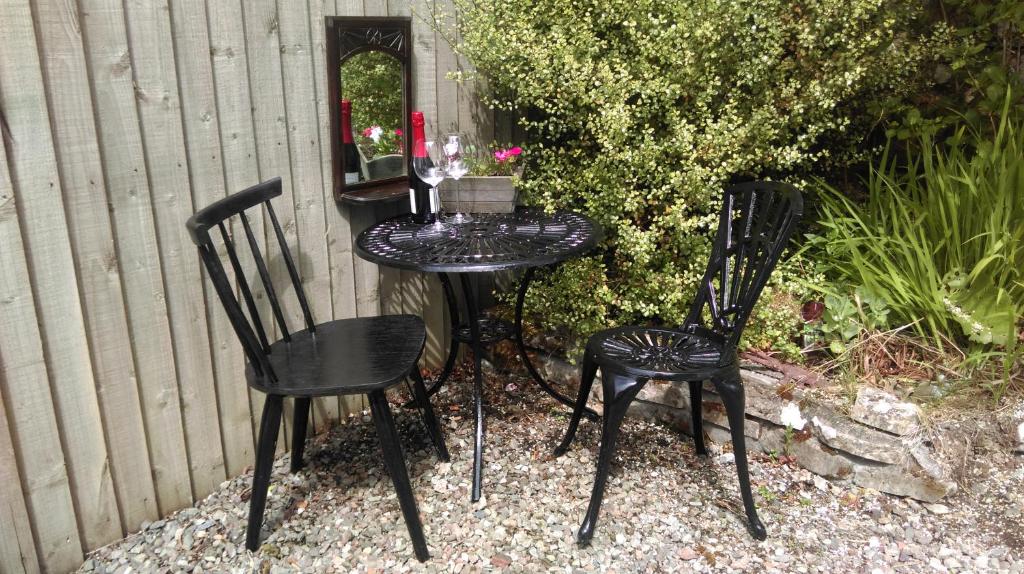 two black chairs and a table with flowers on it at Black Stair Cottage in Helensburgh