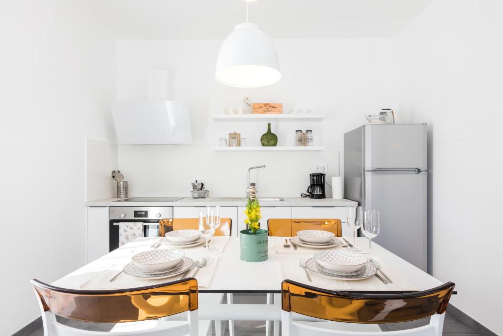 een witte keuken met een tafel en stoelen bij Valbay Residence in Mali Lošinj