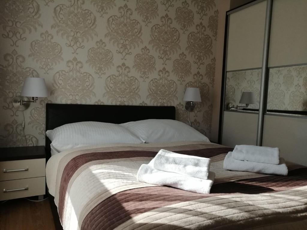 een slaapkamer met een groot bed en 2 handdoeken bij Apartament Mariva B03 z ogródkiem - Pobierowo - blisko morza - przy kompleksie Grand Laola SPA in Pobierowo