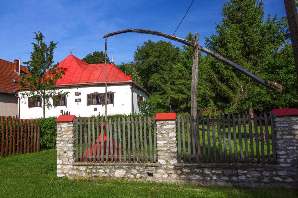 una cerca frente a una casa blanca con techo rojo en Vén Diófa Kúria, en Balaton