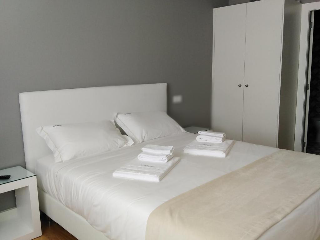 Una cama blanca con tres almohadas encima. en ALM SANTA LUZIA, en Guimarães